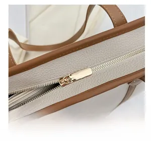 Detail showing smooth golden hardware zipper on white litchi pattern leather tote bag