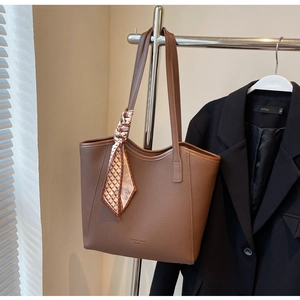 Detail of brown litchi pattern leather tote bag with a decorative checked silk scarf