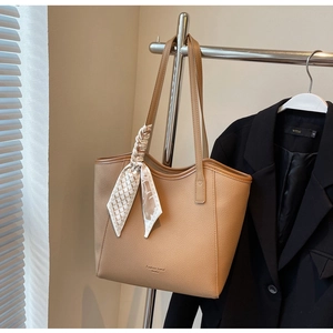 Detail of camel tote bag with lychee texture and decorative geometric scarf on hanger