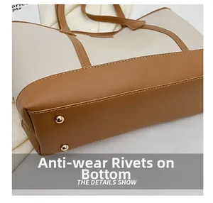 Detail view of the bag's bottom featuring protective gold metal rivets and pebbled leather