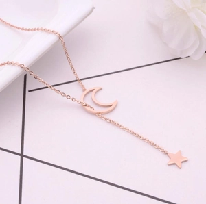 Macro detail of rose gold moon and star pendant charms on a delicate stainless steel chain