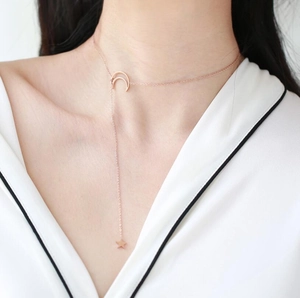 Minimalist rose gold stainless steel star and moon necklace on a female model