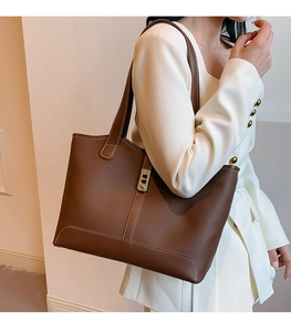 Detail of brown lychee leather tote bag with white contrast stitching and gold clasp