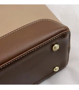 Detail of color-block leather tote bag base with metal feet and lychee texture