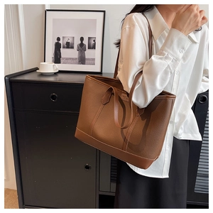 Brown lychee leather tote bag worn by a model in an elegant urban setting
