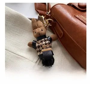 Detail of knitted bunny bag charm with houndstooth vest on a leather shoulder bag