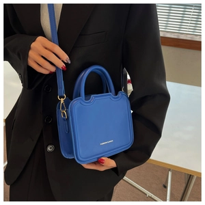 Close-up of bright blue crossbody bag with gold hardware and fashion bags lettering