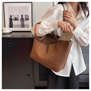 Close-up of brown lychee pattern tote bag worn by a model in a minimalist setting