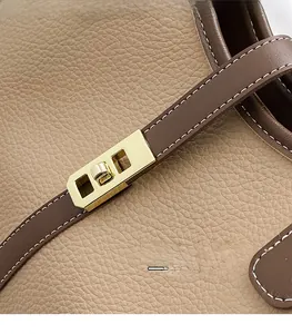 Macro view of gold metal buckle on camel and brown textured leather tote bag
