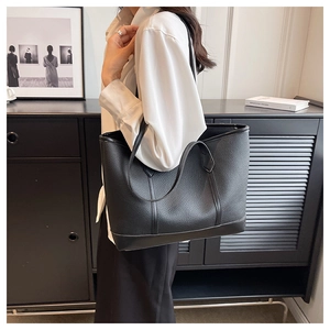 Detail view of black lychee grain tote bag showing large capacity on model shoulder