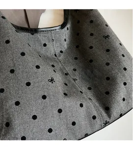 Detail of grey herringbone fabric tote bag with black flocked dots and small bow