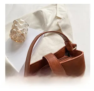 Close-up of brown matte leather bucket bag featuring wide handle and metal zipper