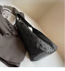 Detail of grey canvas tote bag featuring black polka dots and embroidered bow patterns