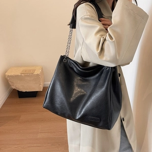 Grande borsa tote nera in pelle martellata con catena argentata indossata da modella