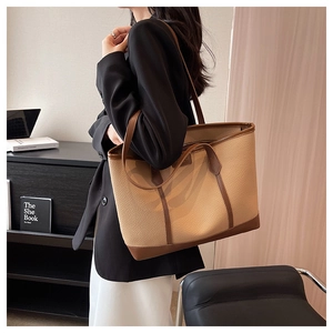 Detail view of large lychee grain leather tote bag worn on shoulder in office setting