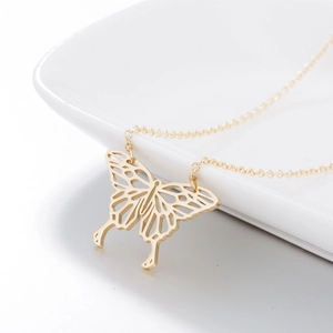 Détail du pendentif papillon doré ajouré sur un plat en céramique blanche