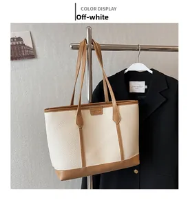 Detail of cream lychee texture tote bag with brown piping and contrast brand patch