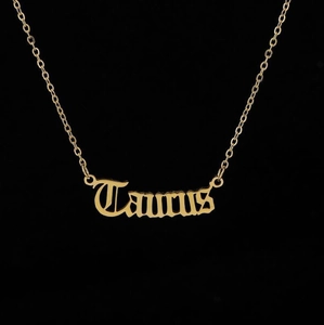 Detailed view of gold Taurus pendant necklace with delicate O-chain on black background