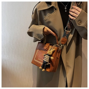 Close-up of retro brown bucket bag with ethnic patterned strap and rabbit charm detail