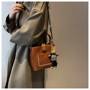 Brown vintage style bucket bag with textured leather and a houndstooth rabbit charm