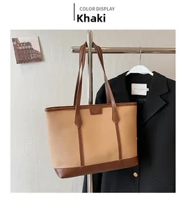 Detail view of the khaki litchi grain tote bag hanging next to a black blazer