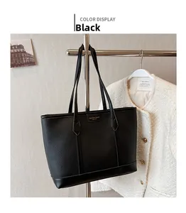 Detail view of large black lychee pattern tote bag with golden logo plaque and thin straps