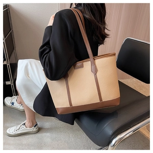 Detail of large tote bag in beige lychee leather with brown contrast stitching and straps