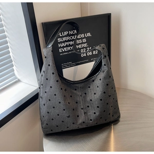 Detailed view of grey polka dot canvas tote bag with bow embroidery on metal desk