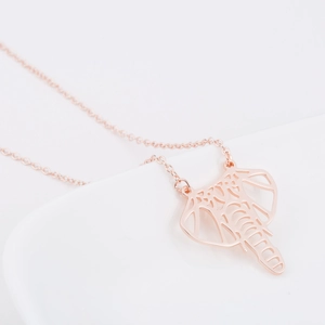 Gros plan du pendentif éléphant en or rose avec motif ajouré complexe sur chaîne fine