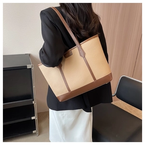 Detailed back view of a beige large-capacity tote bag with brown leather trim and lychee texture