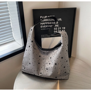 Macro view of grey canvas shoulder bag with black star patterns and leather strap
