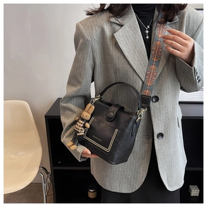 Detail of black leather bucket bag featuring vintage patterned strap and bunny charm