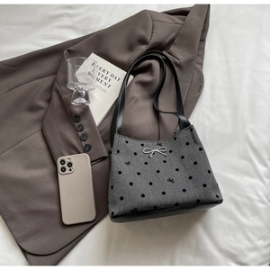 Detailed shot of a grey tweed bucket bag with black polka dots and silver bow hardware
