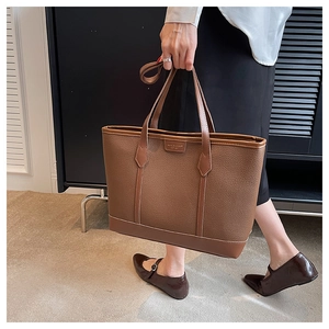 Deep brown lychee grain leather tote bag shown by a model in a minimalist setting