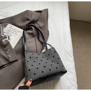 Detail of grey polka dot tweed fabric with bow embroidery and black leather strap