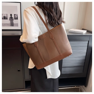 Detail of lychee textured brown tote bag with premium metal logo and stitching
