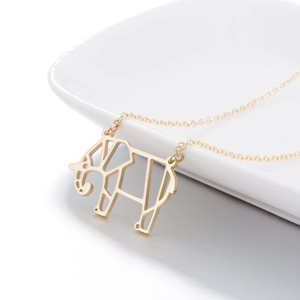 Détail d'un collier pendentif éléphant doré géométrique sur une assiette en céramique blanche