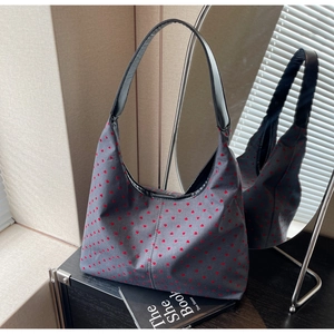 Detailed view of red heart pattern on grey canvas tote bag with black leather handle