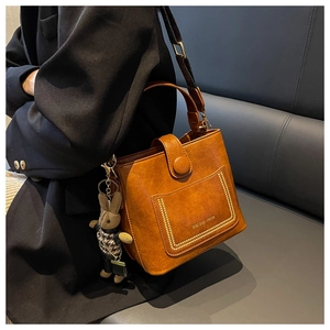 Detail of vintage brown leather bucket bag with wide strap and cute rabbit pendant