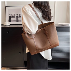 Detailed side view of a brown lychee pattern tote bag worn by a model in a modern room