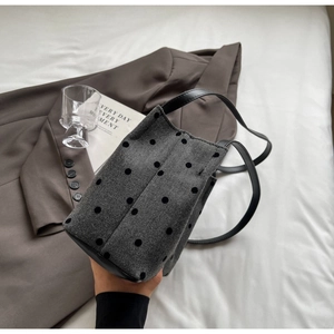 Close-up of textured herringbone bucket bag with black flocked dots and leather handles