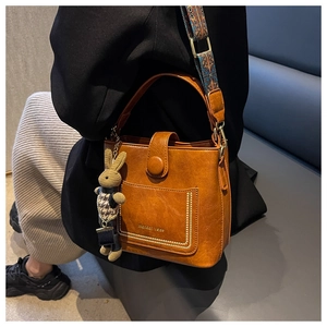 Detail of brown leather bucket bag with Mandun Verse logo and ethnic print strap