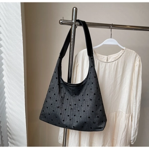 Detail of dark grey canvas tote bag with polka dots and black shoulder strap on a hanger