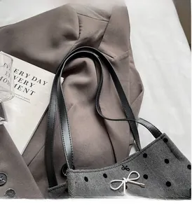 Macro shot of grey herringbone fabric texture with black velvet dots and metal bow detail