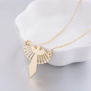 Détail du pendentif papillon doré ajouré sur porcelaine blanche avec chaîne fine