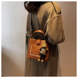 Detail of vintage brown bucket bag with gold accents and teddy bear charm on model