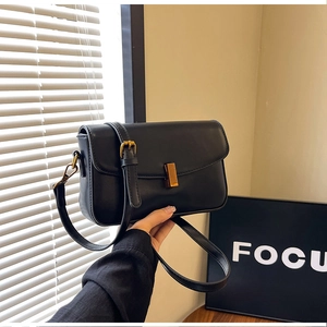 Detail of minimalist black leather crossbody bag with elegant gold metal buckle closure