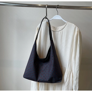 Detail of dark blue canvas tote bag featuring embroidered red hearts and black leather straps
