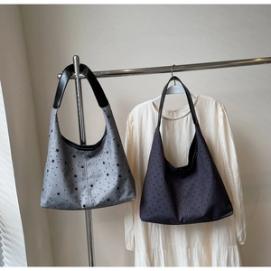 Detail of canvas tote bags featuring star and heart patterns on minimalist display racks
