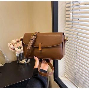 Detail of a brown vintage leather crossbody bag featuring a classic gold rectangular clasp